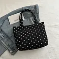 Black polka dot tote bag in corduroy fabric shown on casual denim jeans setting - Black