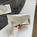Silberne Umschlag-Clutch mit metallischer Wellenstruktur und goldener Herz-Schnalle - Silber