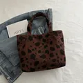 Brown corduroy shoulder bag with black cow print texture shown on denim fabric - Brown
