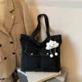 Large black denim tote bag with plush charm and front flap pockets on a silver suitcase - With Cloud Pendant / Black