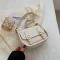 Minimalist cream white shoulder bag with dual buckle straps on a soft textured fabric - White