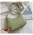 Gros plan d'un sac demi-lune vert clair en cuir avec des boucles dorées sur tissu - Vert