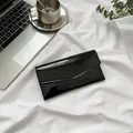 Portafoglio a busta in pelle verniciata nera lucida su un moderno set da scrivania - Nero