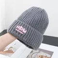 Detailed close-up of grey ribbed knit beanie featuring a pink 'HioW' embroidered patch - One Size / Gray