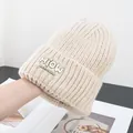 Close-up of beige thick ribbed knit beanie featuring a stylish rectangle brand patch - One Size / Beige