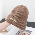 Detailed view of dark brown knitted beanie with textured ribs and a yellow lettered patch - One Size / Camel