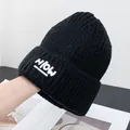 Nahaufnahme einer schwarzen Strickmütze mit weißem HiOW-Aufnäher und umgeschlagenem Rand - Einheitsgröße / Schwarz
