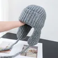 Detailed close-up of grey knit trapper hat with thick wool texture and braided earflaps - M (56-58cm) / Gray