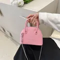 Pink lychee texture mini shell bag with chain strap held by hand in soft light - 15.5cm x 12cm x 7cm / Pink