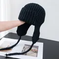 Detailed view of thick knit black trapper hat with earflaps and long braided ties - M (56-58cm) / Black