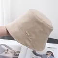 Detailed view of beige cotton bucket hat texture with a premium leather logo patch - Adjustable / Light Khaki