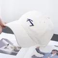Dettaglio del cappellino in cotone crema con ricamo blu navy 'Funny' fatto a mano - Regolabile / Bianco Sporco