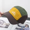 Detalle del bordado en una gorra de campamento de cinco paneles en tejido técnico - Ajustable / Café y Amarillo