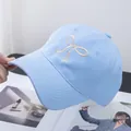 Detailed close-up of light blue baseball cap with white ribbon bow embroidery and stitching - Adjustable / Blue