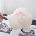Close-up of pink bow embroidery on a beige soft top baseball cap with cotton texture - Adjustable / Beige