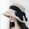 Detail of beige sun hat with large black bow and UV protection tag on side - Adjustable / Beige