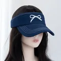 Close-up of navy denim sun visor hat with white embroidered bow and stitched brim - Adjustable / Dark Blue