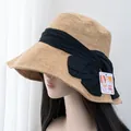 Detail of khaki straw sun hat with black bow and UV 99% protection certification tag - Adjustable / Khaki