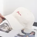 Detail van rood me borduursel op een crème katoenen baseballpet met gebogen klep - Verstelbaar / Beige