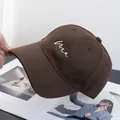 Detailopname van de bruine katoenen baseballpet met wit geborduurd 'Me' tekstontwerp - Verstelbaar / koffiekleur