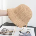 Dettaglio di un cappello a secchiello in paglia intrecciata con laccetto beige - M / Cachi