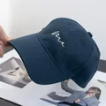Detailed view of white 'me' embroidery on navy blue cotton baseball cap with curved brim - Adjustable / Navy Blue