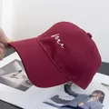 Close-up of wine red cotton baseball cap with white cursive me embroidery and curved brim - Adjustable / Burgundy