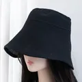 Close-up of the dense knit texture and wide brim of the black sun hat on a model - M (56-58cm) / Black