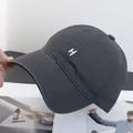 Κοντινό πλάνο λευκού κεντήματος γράμματος Η σε σκούρο γκρι βαμβακερό καπέλο μπέιζμπολ - σκούρο γκρι