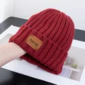Detailed texture of dark red ribbed knit hat with a premium brown faux leather patch - Stretchy / Burgundy