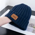 Macro detail of navy blue ribbed knit beanie with brown leather logo patch - Stretchy / Navy Blue