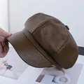 Detailaufnahme der tiefbraunen PU-Leder-Schirmmütze mit texturierten Paneelen und Knopf - Kaffeebraun