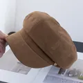 Detailopname van de bruine suède krantenjongenspet met gouden gesp aan de zijkant en textuur - camel