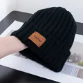 Close-up of black ribbed knit beanie featuring a brown vintage leather brand patch - Stretchy / Black