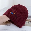 Gros plan d'un bonnet en tricot bordeaux avec broderie détaillée de petit teckel - Bordeaux