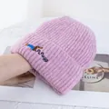 Gros plan du bonnet en tricot rose avec broderie de chiot et détail du texte GREGG - Rose