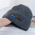 Détail de la broderie teckel sur un bonnet en maille côtelée gris foncé en laine douce - Gris clair