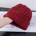 Dettaglio del berretto in maglia bordeaux con trama a coste e ricamo rosso fine - Borgogna