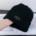 Dettaglio del berretto in maglia nera con ricamo bianco e trama a coste spessa - Nero