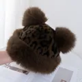Close-up of leopard print faux fur winter hat with large pompoms and plush ear flaps - M(56-58cm) / Coffee