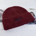 Close-up of burgundy knit wool beanie featuring blue NEW YORK 1986 letter embroidery - Stretchy / Burgundy