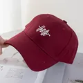 Detail of burgundy baseball cap with white artistic embroidery and reinforced brim stitching - Burgundy