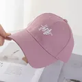 Detail of pink cotton baseball cap featuring white abstract embroidery and reinforced brim - Pink