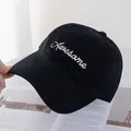 Detail of white Awesome embroidery on a black cotton baseball cap over a magazine - Black