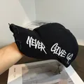Primer plano de la visera desgastada y bordado Never Give Up en gorra negra - Ajustable / Negro
