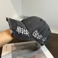Detail of distressed brim and white NEVER GIVE UP embroidery on vintage washed baseball cap - Adjustable / Denim Gray