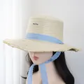 Détail d'un chapeau de paille à haut plat avec ruban vichy bleu et bord effiloché - M (56-58cm) / Beige