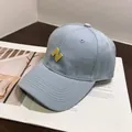 Detailed close-up of light blue cotton baseball cap with yellow N embroidery and stitching - Normal Circumference / Blue