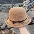 Detail van een kaki strooien cloche hoed met een donkerbruine strik en fijn weefsel - M (56-58cm) / Donker kaki