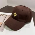Primer plano del bordado en 3D de la letra N amarilla en una gorra de algodón marrón oscuro - Café